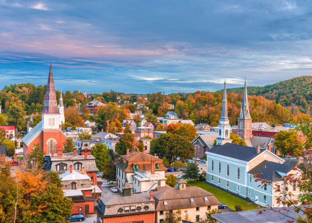 An aerial view of a small town with few church towers surrounded by trees in fall.