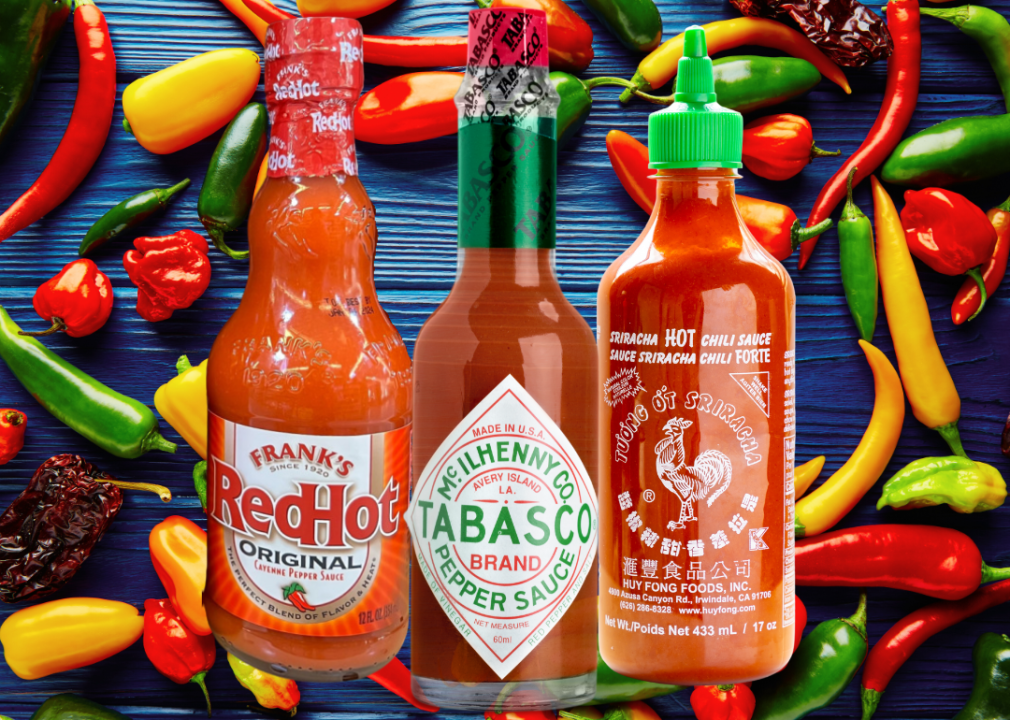 Three hot sauce bottles against a background of hot peppers.