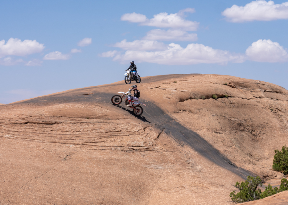 Off road motorcycles climbing steep sandstone near Moab, Utah.