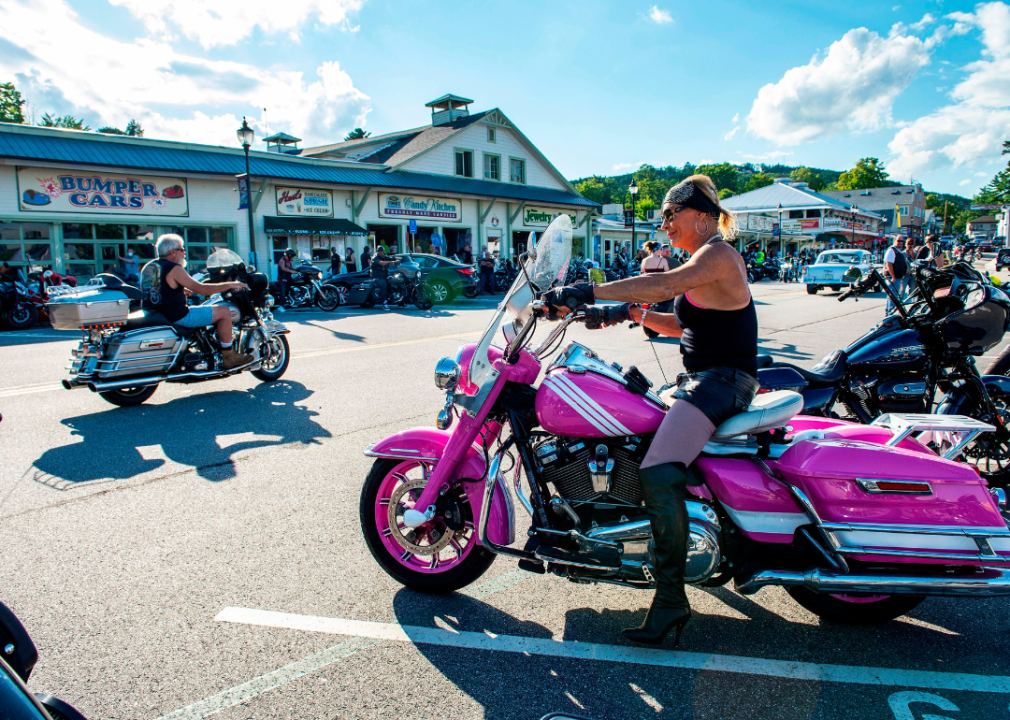 A woman on a pink motorcycle pulling onto a road in NH during a bike week.