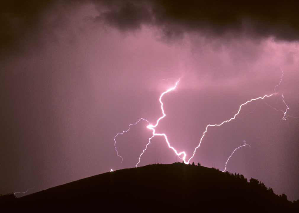 Lightning striking a hilltop bristling with towers for lightning.