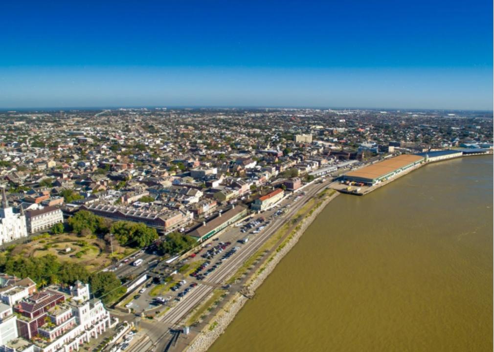 An aerial view of a city by a river with a road running along its banks.