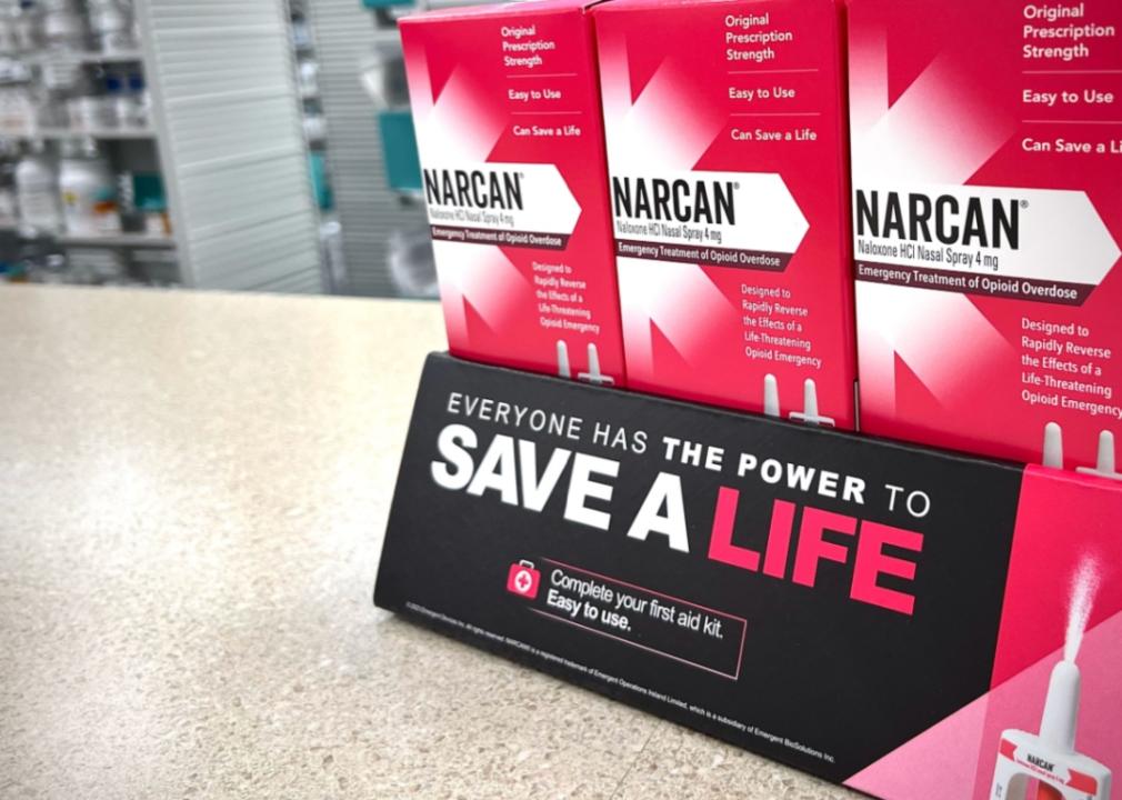 A close up of three boxes of Narcan medication on the counter at a pharmacy with a sign saying, everyone has a power to save a life.