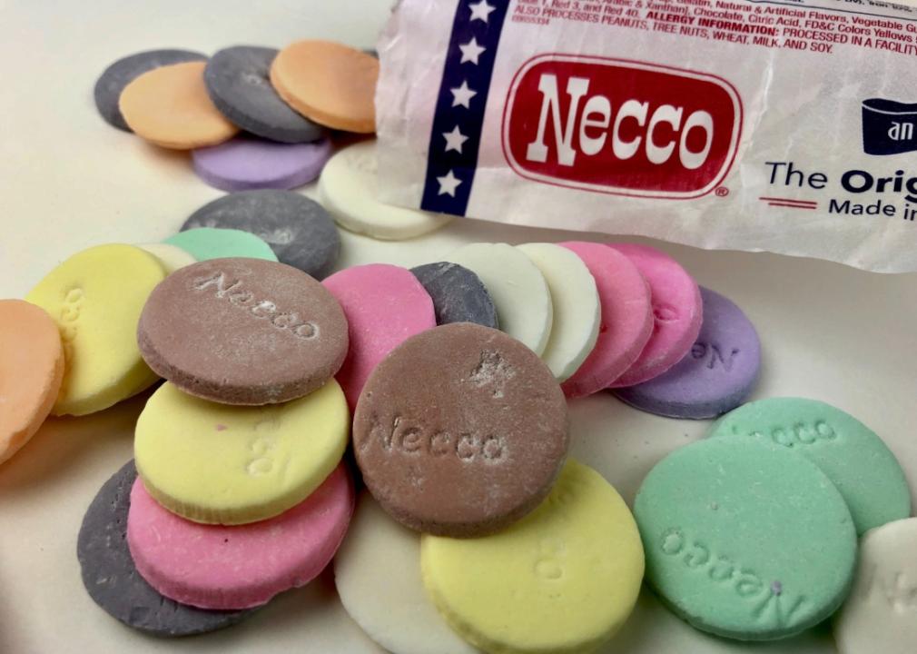 A bag with the words "Necco" surrounded by round colorful cookies with necco lettering on them.  