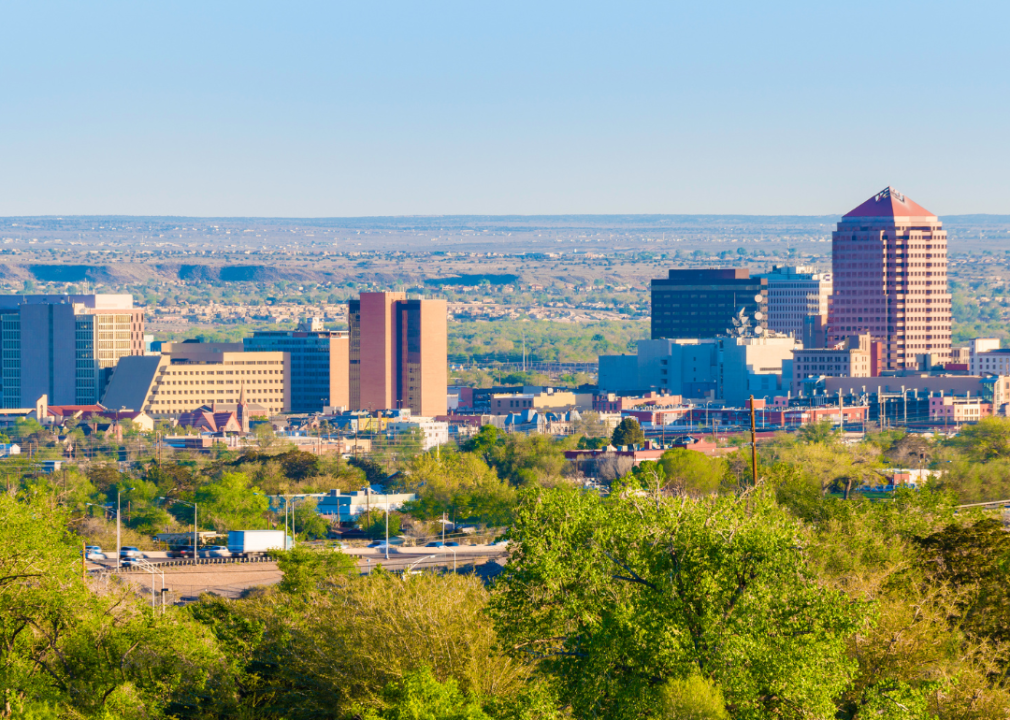 A city skyline with tall buildings and trees in the foreground.