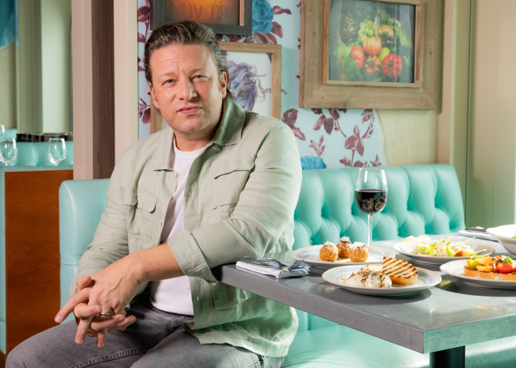 Jamie Oliver sitting at a booth table.