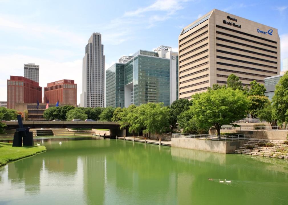 A city with a river flowing through it. Several buildings of different styles line the riverbank with a bridge crossing the river.