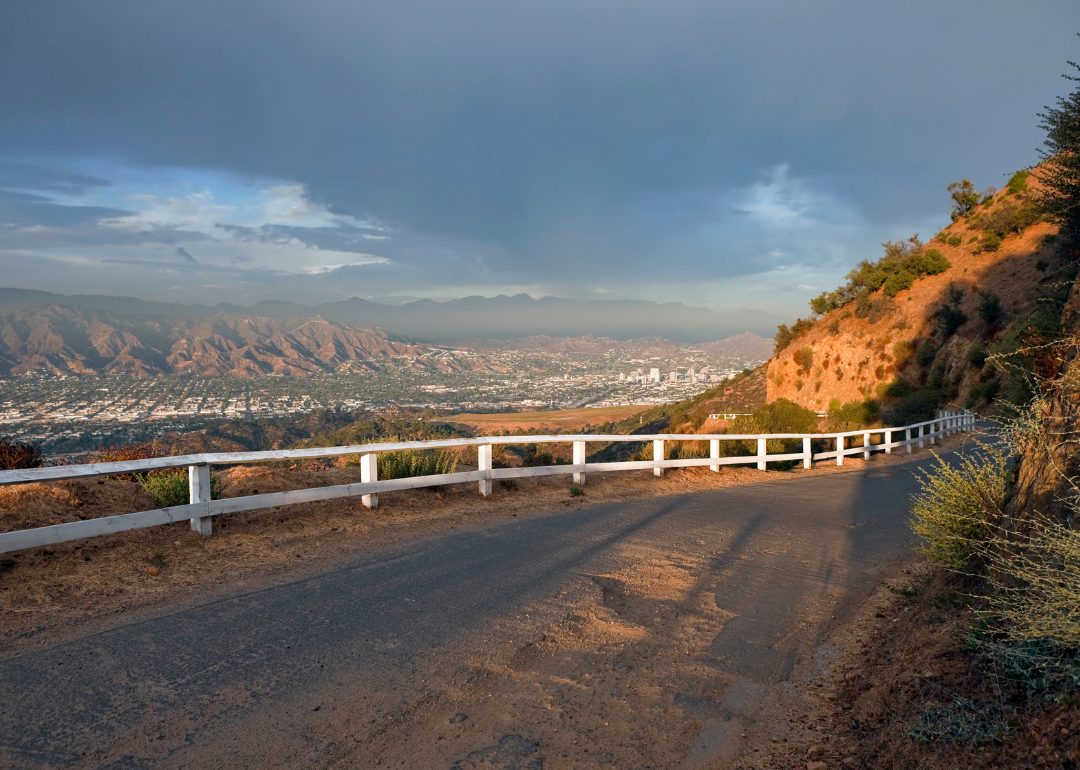 A white fence on a mountain road with Glendale in the distance.