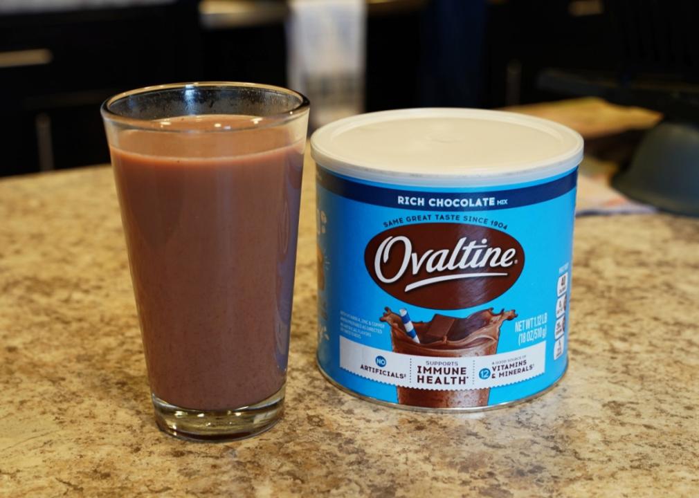 Ovaltine rich chocolate milk mix and a glass of milk sit on kitchen countertop.