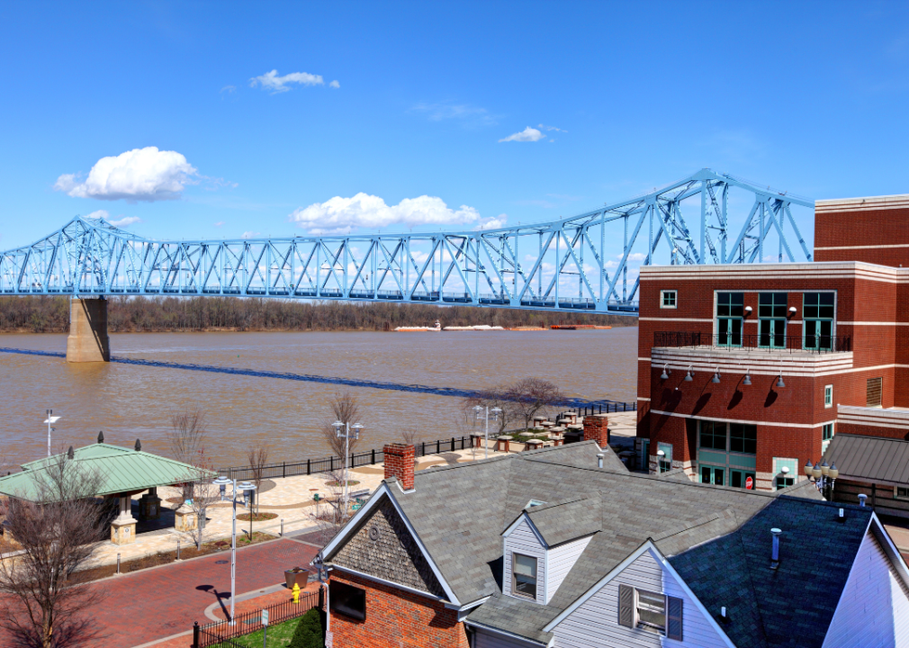 The foreground of the image shows the steel bridge, and the background shows the river and the shoreline. 