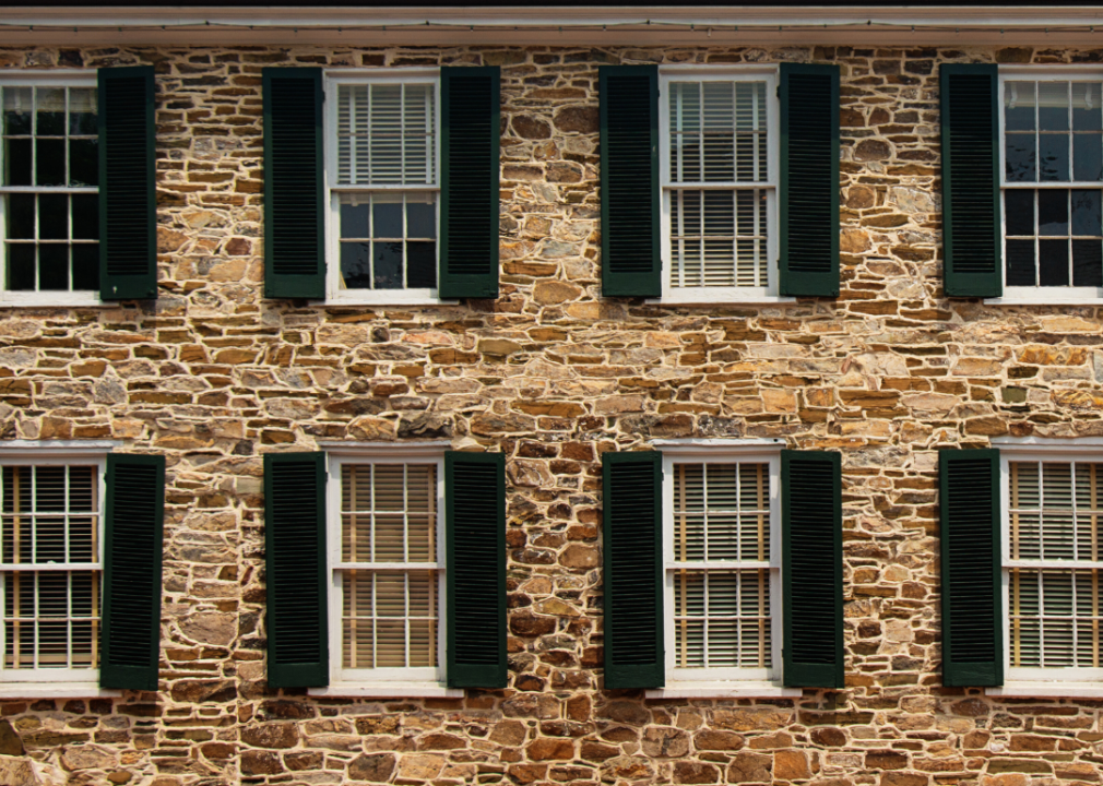 A stone home with black shutters.