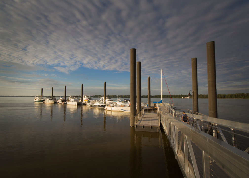 A long wooden pier over a calm body of water with docked boats.