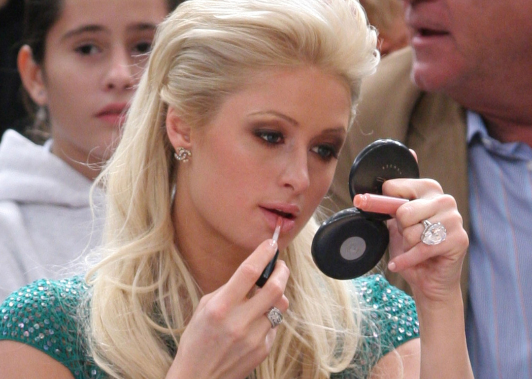 Paris Hilton applying makeup while attending a basketball game