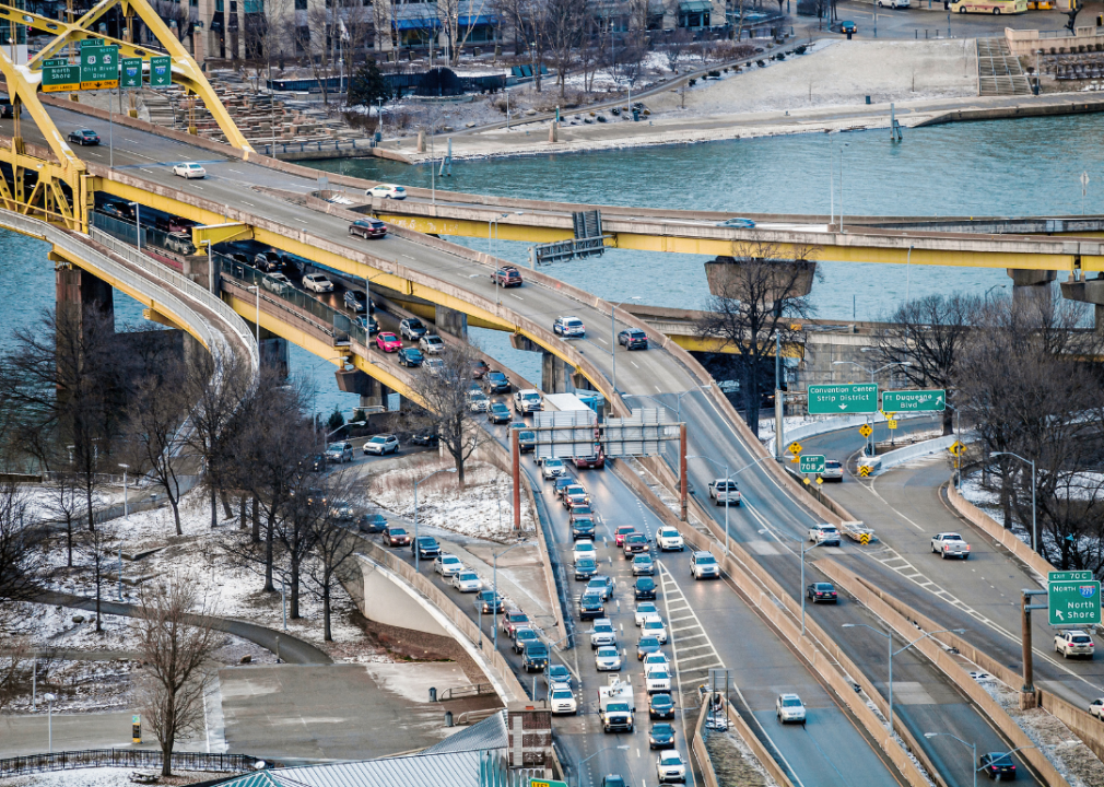 A busy highway going over a yellow bridge over a river in Pittsburgh.