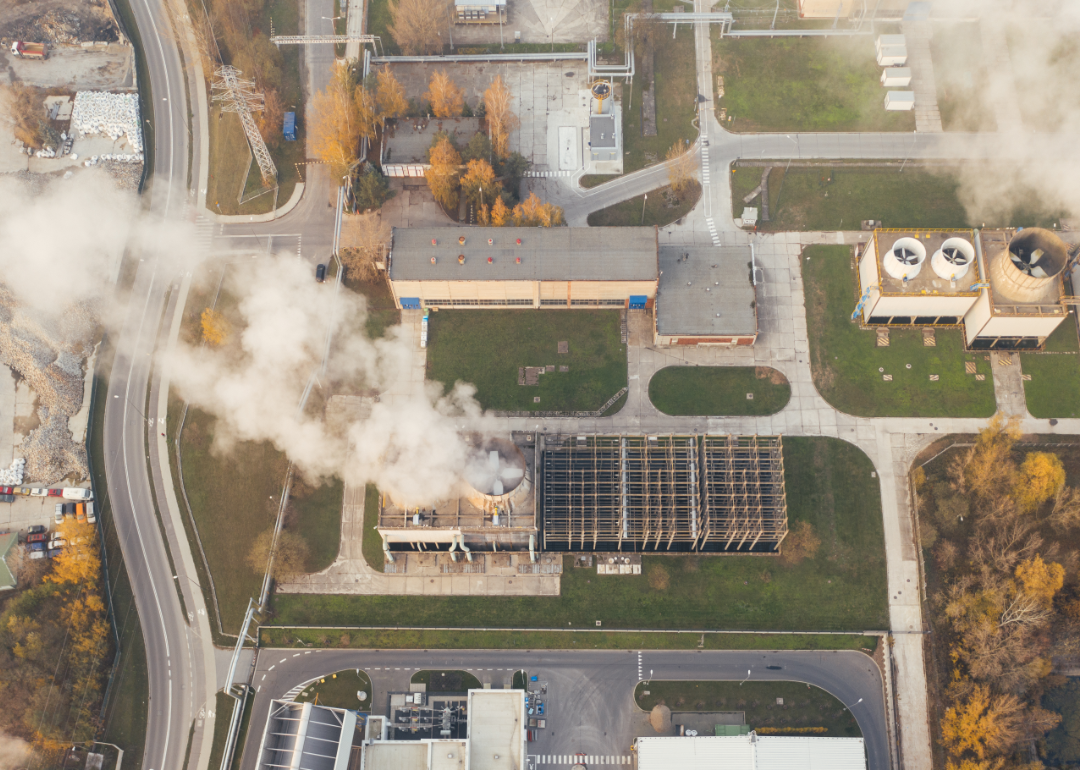 Aerial view of white smoke emanating from an industruial building.