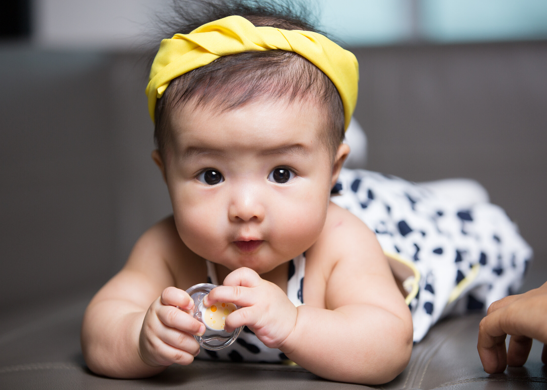 Happy baby holding pacifier laying down.