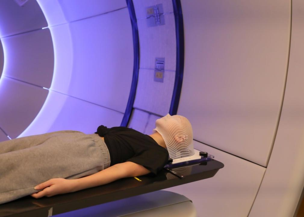 A young female patient is lying under large lamps emulating violet light. 