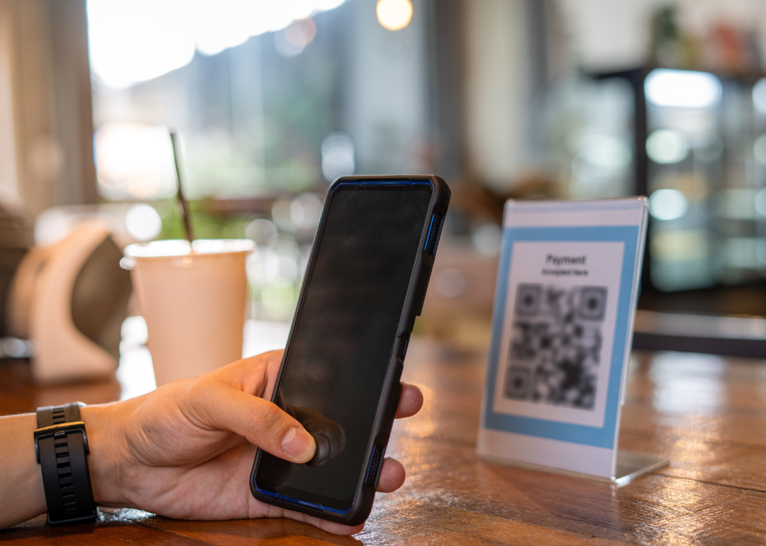 A person scanning a QR code with a cell phone at a coffee shop.
