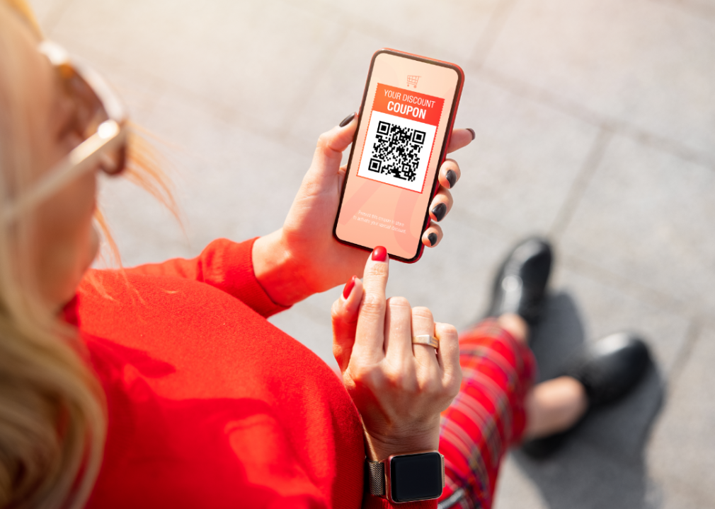 A woman looking at a QR code coupon on her smartphone.