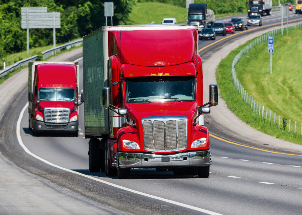 Two red large trucks on the highway. 