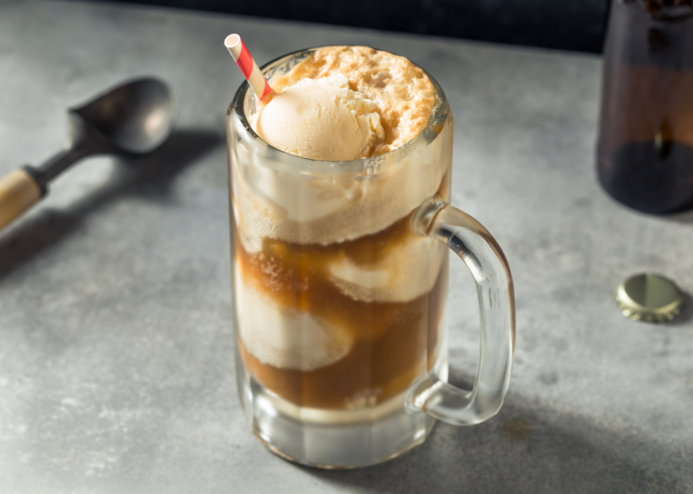 Clear glass mug with brown liquid and ice cream scoops floating. 