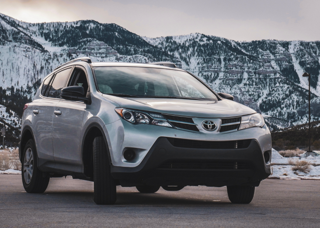 A silver Toyota RAV4 with mountains in the background.