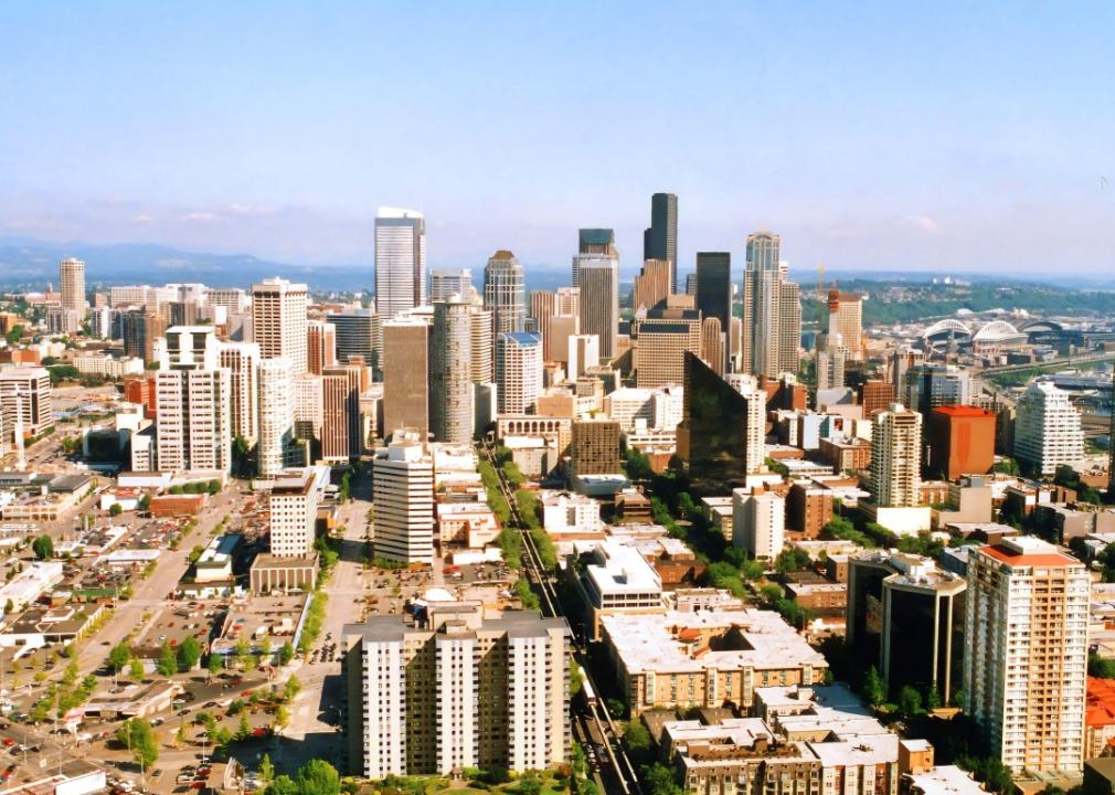 City skyline dominated by a cluster of tall skyscrapers in the center, with a mix of shorter buildings and structures spreading out towards the edges of the image. A network of roads crisscross the city. 