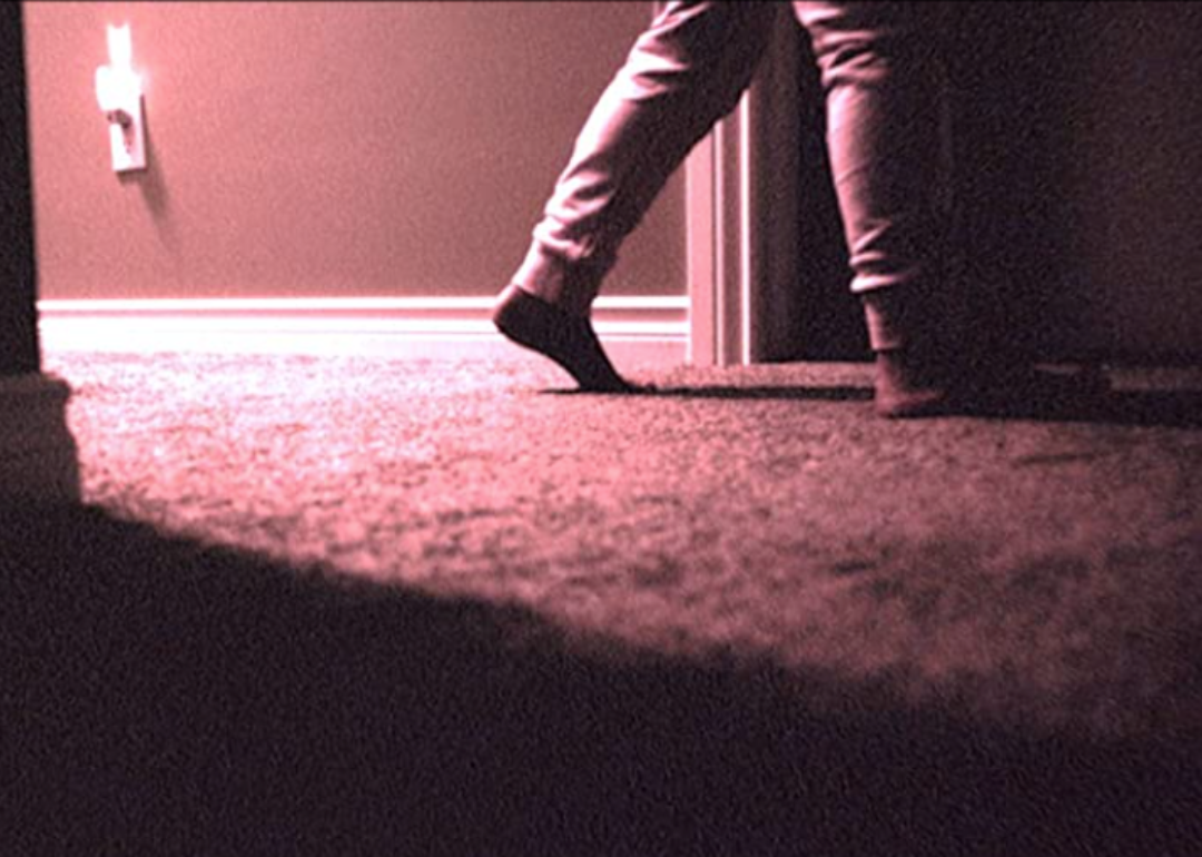 A scene from Skinamarink showing a someone's feet tip toeing across the carpet.