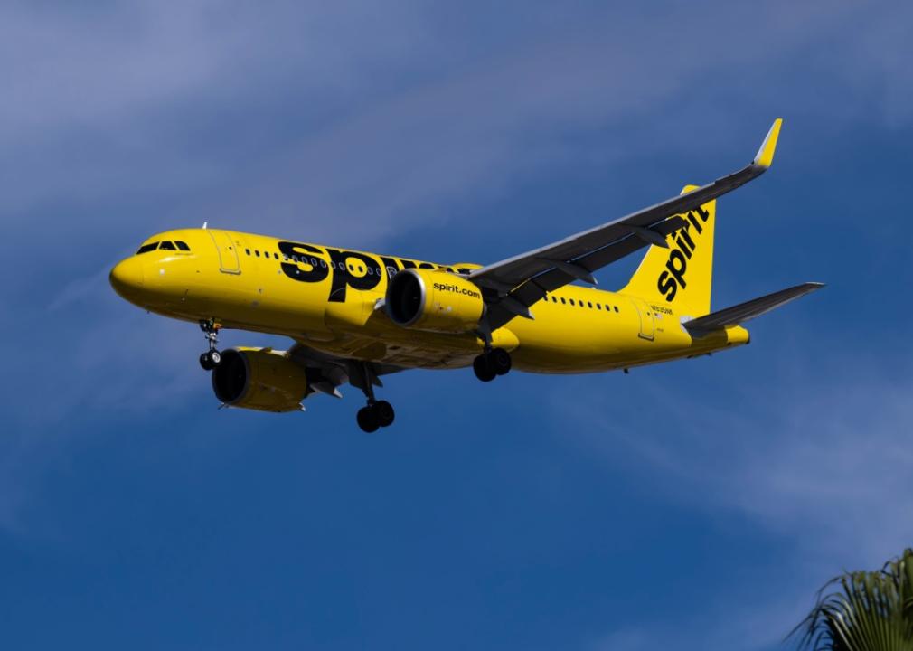 Bright yellow Spirit Airlines airplane in flight aginst blue skies.