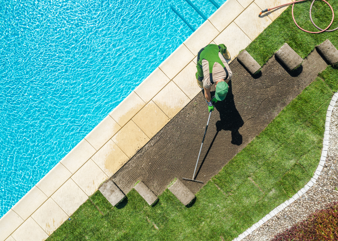 Landscaper installing grass around a pool.