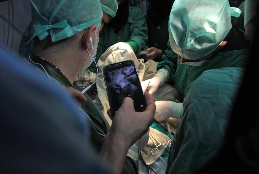 A surgeon holds his phone up during surgery.