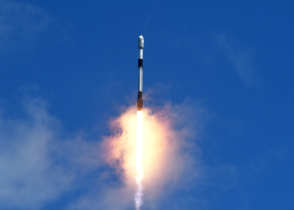 A SpaceX Falcon 9 rocket carrying Starlink internet satellites launching into a blue sky.