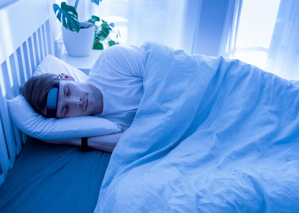 A man sleeping in bed with a wearable tech device around his head.