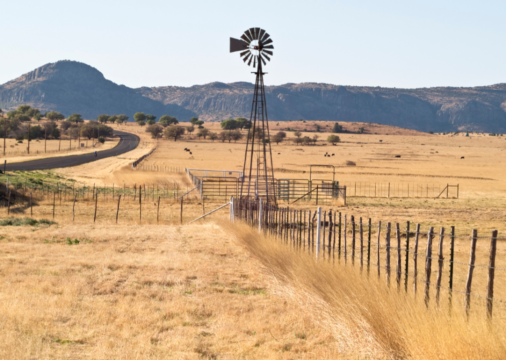A windmill in the middle of a dry grass field. 