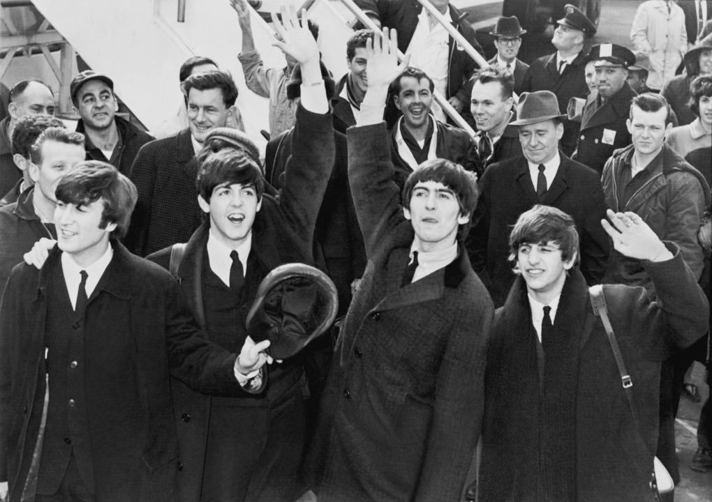 The Beatles wave to fans at an airport