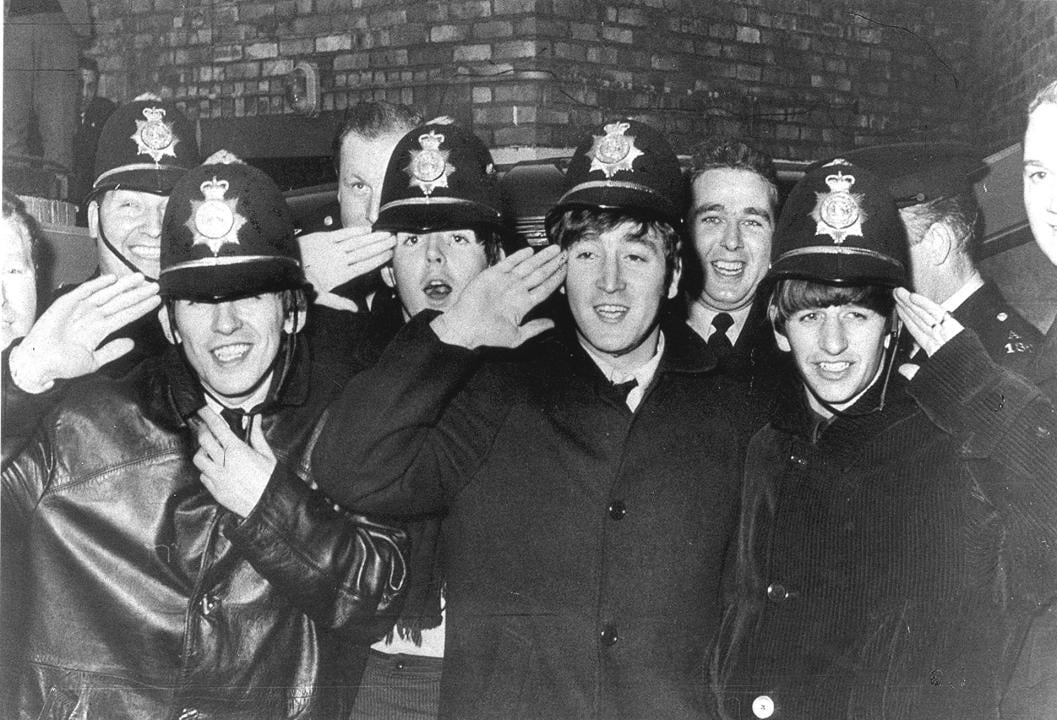 The Beatles pose with British p[olice wearing Bobby hats