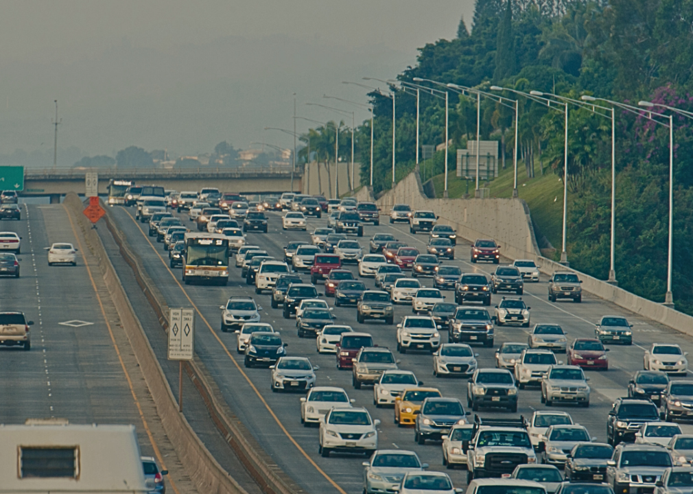 A busy highway with heavy traffic in both directions. Above the highway, there is an electronic sign displaying a message.