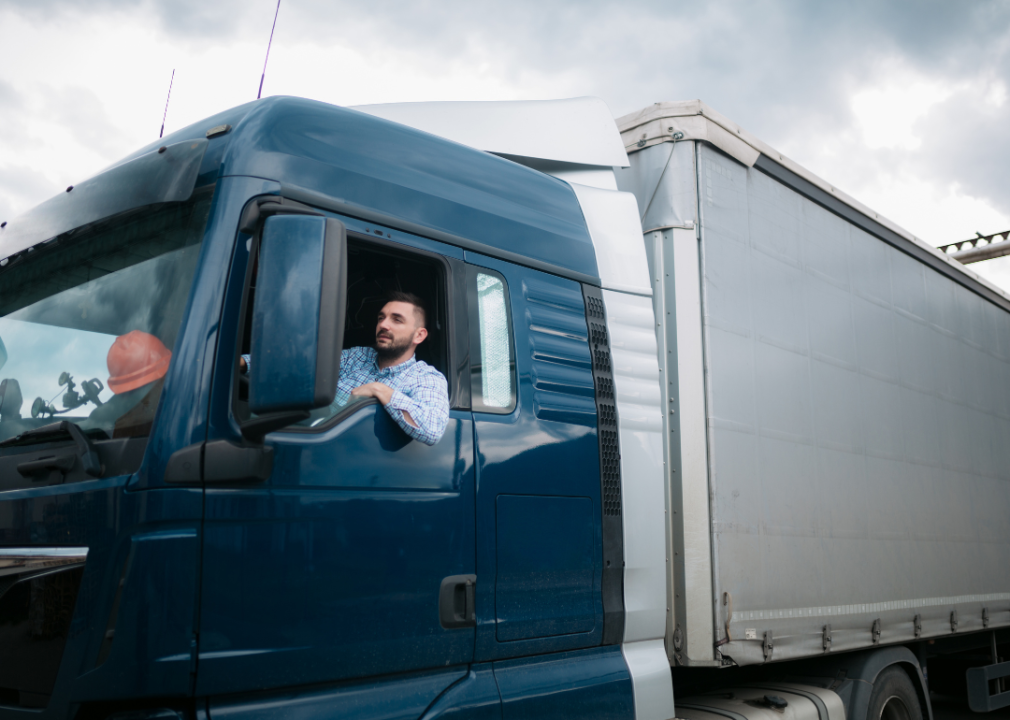 A male driver sitting in a truck looking forward.