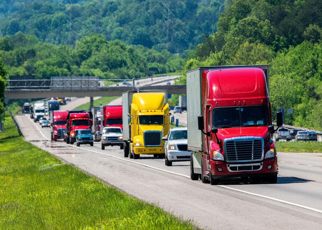 A red semi leading the traffic on an interstate highway.