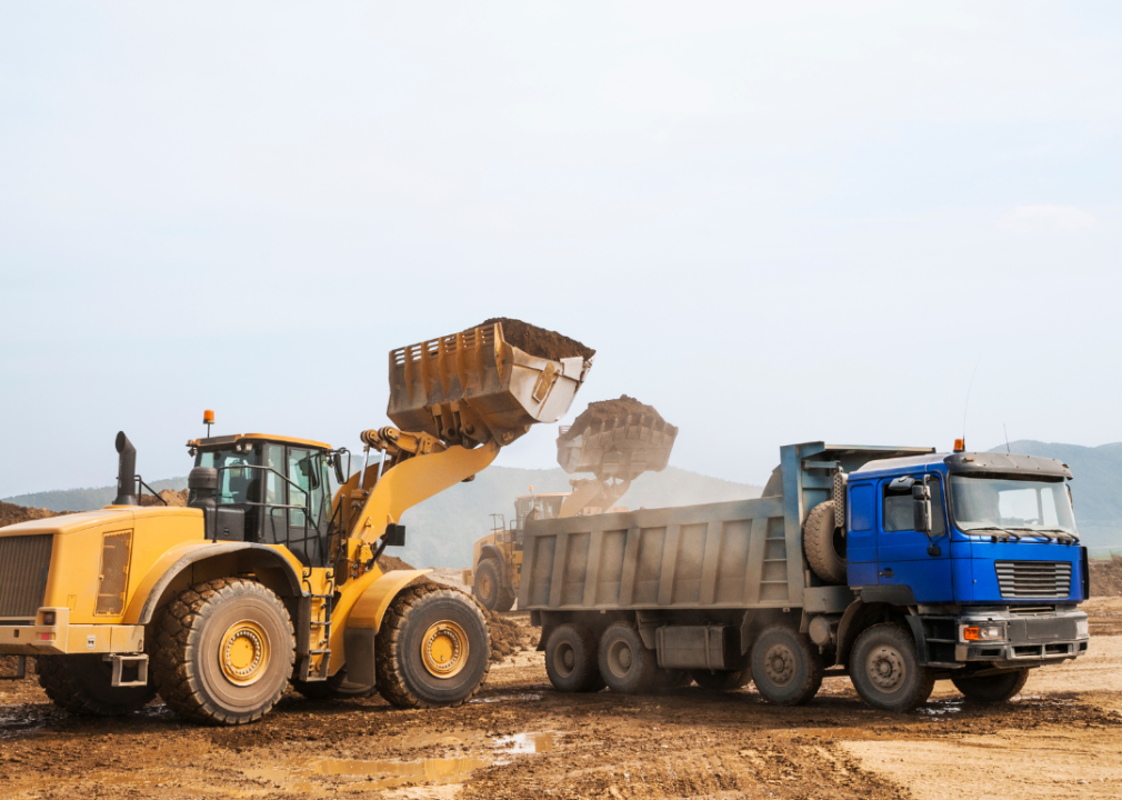 A close-up of a tipper truck and loaders on a dirt ground.