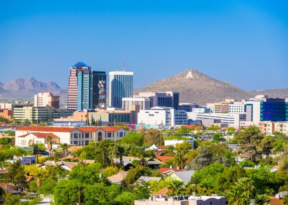 A city with a mix of building heights, from low-rise residential areas to taller office buildings in the downtown area. A mountain peak rises in the background.