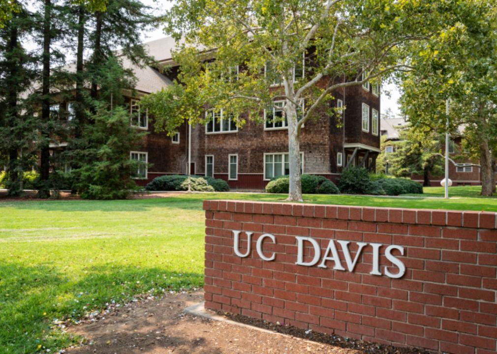 A brick gate entrance to U.C. Davis with a brick building in the background.