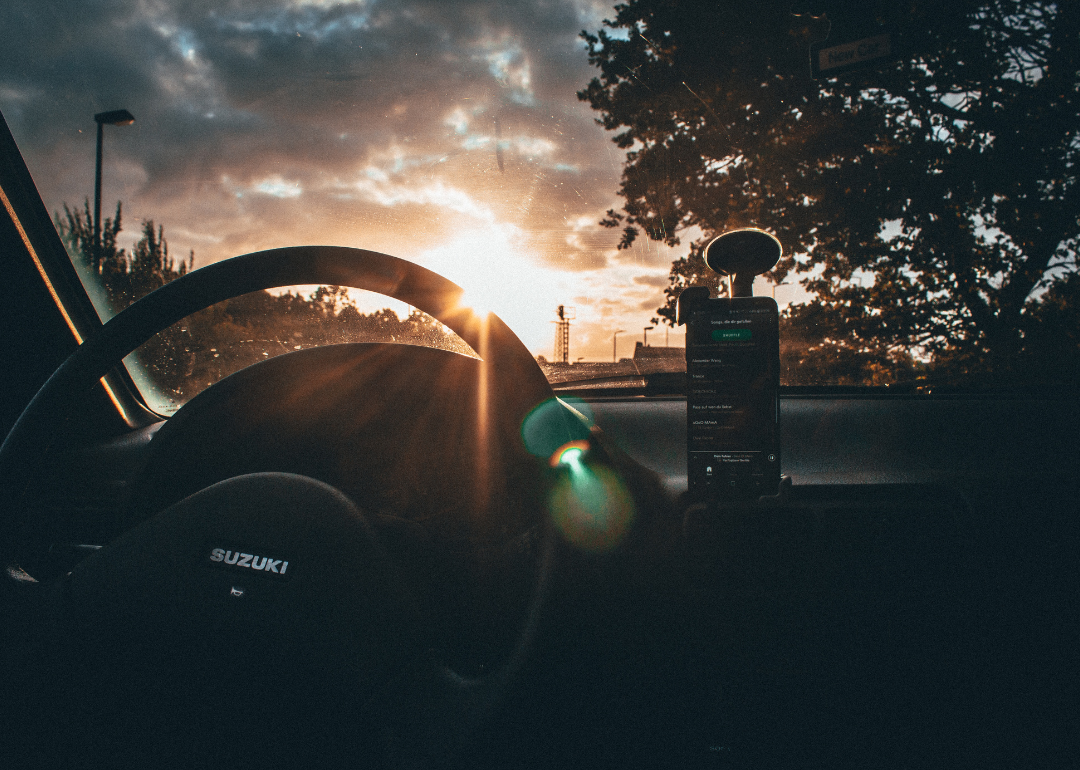 The interior of a black Suzuki car at sunset.