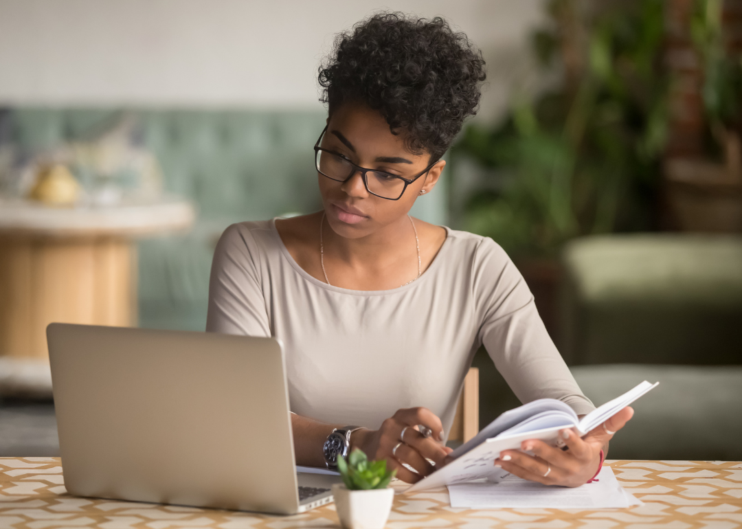 A businessperson reviews their notes in front of a laptop.