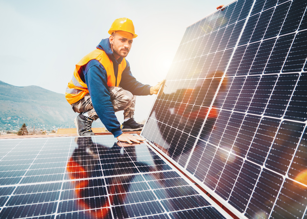 A worker assembling solar panels on top of a building