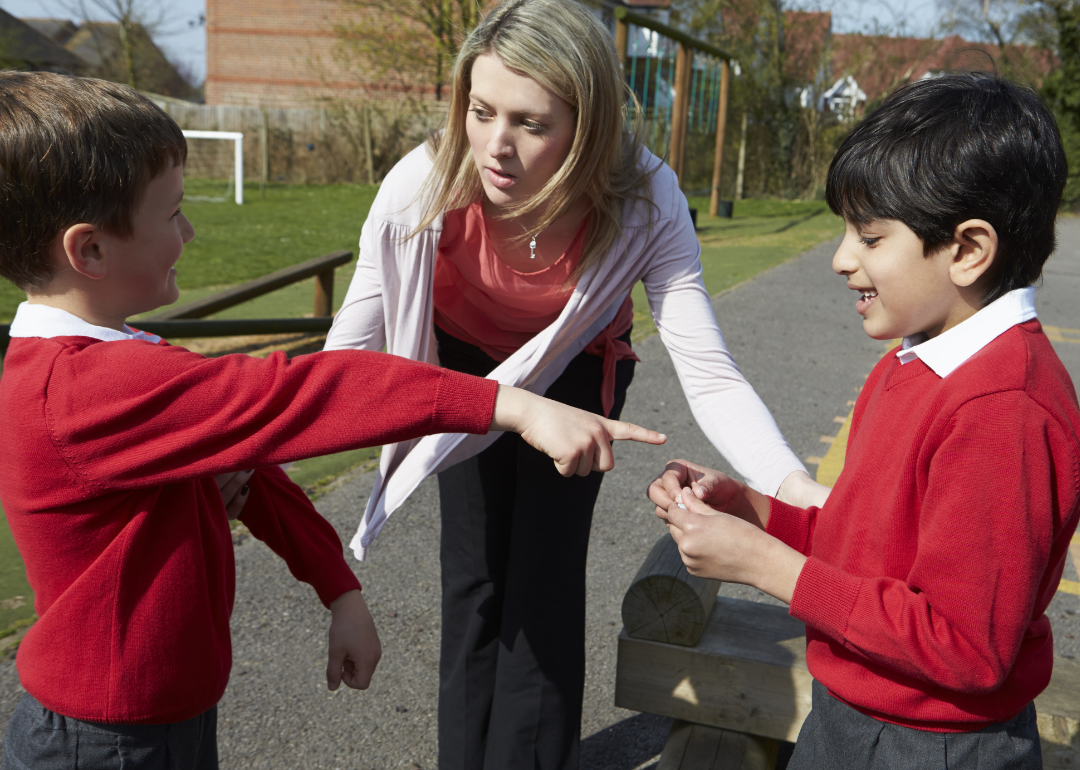 A teacher stopping two boys from fighting.