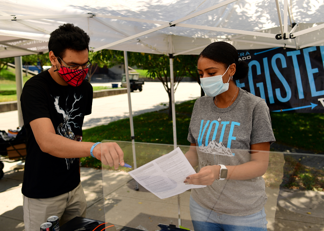 Jazmyne Brooks of New Era Colorado, right, helping Saul Alfaro fill out a voter registration form at Auraria Campus in Denver, Colorado