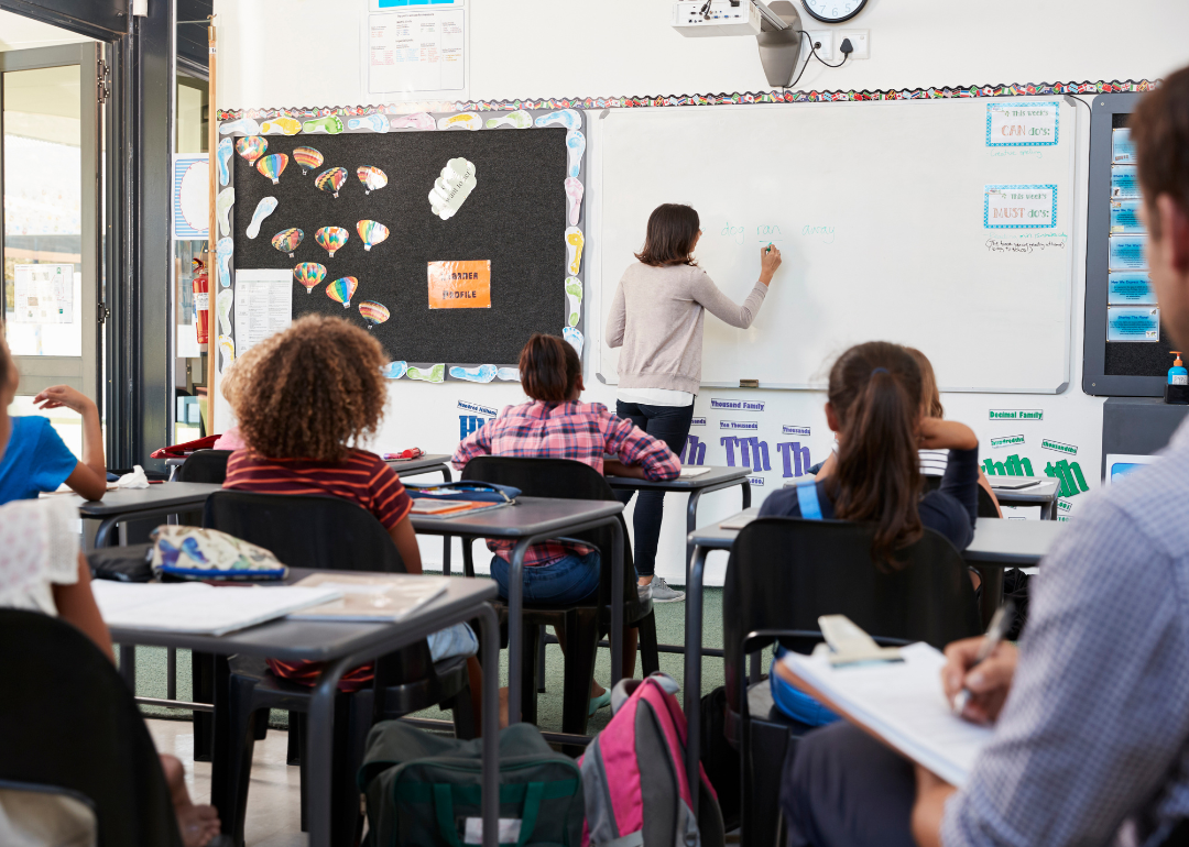 A teacher writing on a white board.