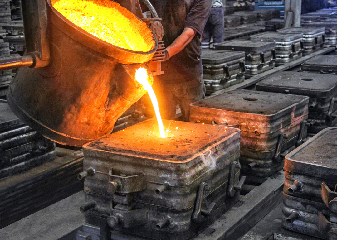 A worker pours molten metal into a cast.