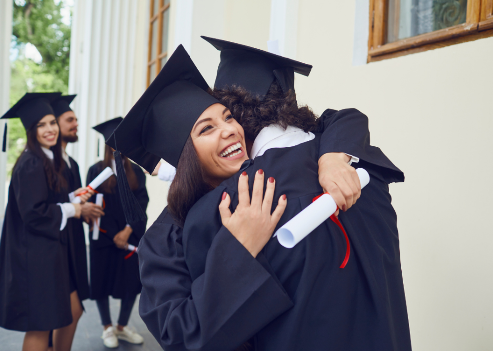 A girl hugging someone after graduating and receiving her diploma